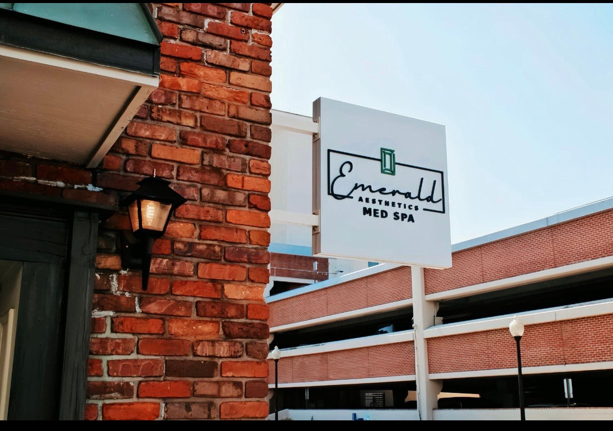 Emerald Aesthetics Med Spa sign installed as projecting blade sign on brick building